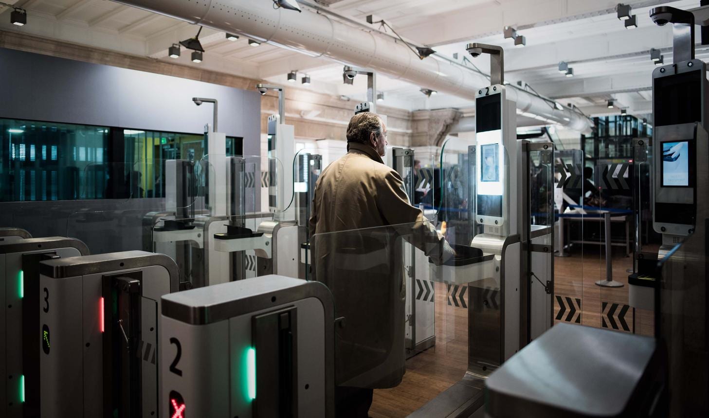 A traveler passing through automated biometric passport gates under a row of cameras